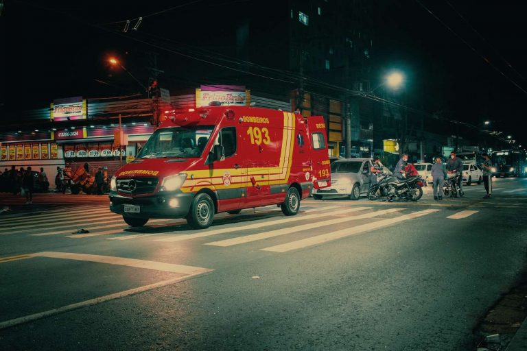 Red emergency transport near car crash on illuminated night street in modern city